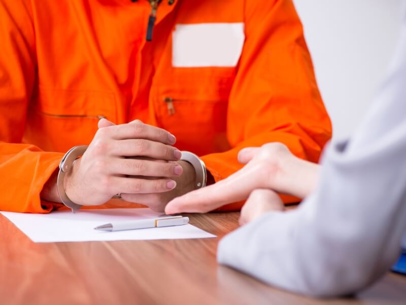 A lawyer and their client seated in a courtroom engaged in a serious conversation about the ongoing trial