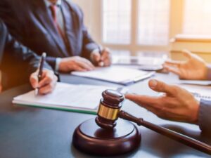 A lawyer stands before a judge in a courtroom engaged in a legal discussion with courtroom decor in the backgroun