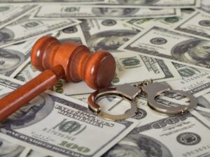 Gavel and handcuffs atop scattered $100 bills, symbolizing legal consequences of financial crime.